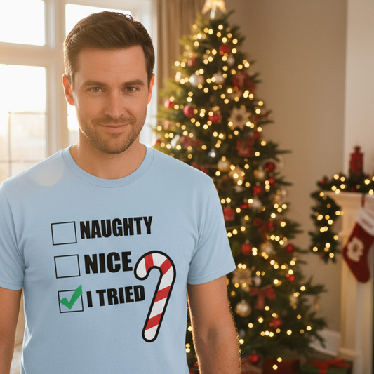 Man wearing a light blue t-shirt with Christmas-themed text in a festive room with a decorated tree.