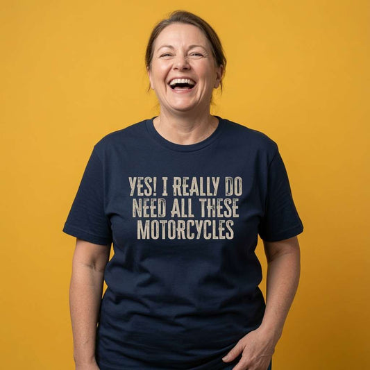 Woman laughing with both hands on her hips while wearing a navy Yes! I Really Do Need All These Motorcycles t-shirt, fun ladies relatable biker slogan design full of pure attitude