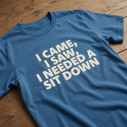 Blue I Came, I Saw, I Needed a Sit Down t-shirt laid flat on a wooden surface, clean white text that delivers perfect sarcastic age banter for women