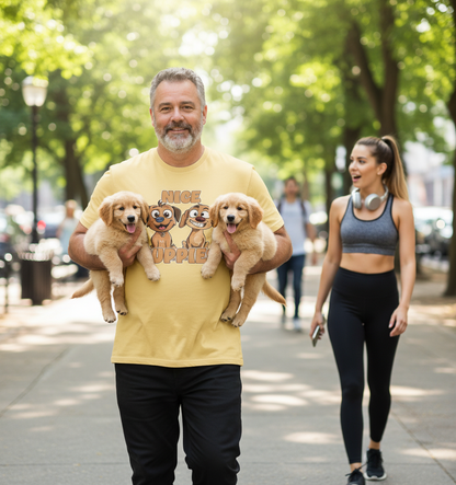 Man holding three puppies and wearing a yellow t-shirt with cartoon dogs, walking on a sidewalk with a woman in the background.