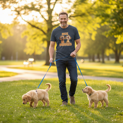 Man walking two puppies in a park with trees and grass in the background