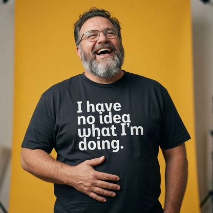 Man laughing with one hand on his stomach while wearing a black I Have No Idea What I’m Doing t-shirt, funny mens cheeky relatable slogan design that every cheeky lad will claim