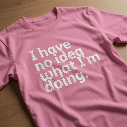 Pink I Have No Idea What I’m Doing t-shirt laid flat on a wooden surface showing the full white slogan, witty ladies funny slogan design full of pure attitude