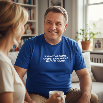 Man wearing a blue t-shirt with text, sitting on a couch with a woman, in a home setting.