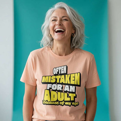 Woman laughing with silver hair while wearing a peach Often Mistaken For An Adult Because Of My Age t-shirt, sarcastic ladies birthday slogan gift design full of pure attitude