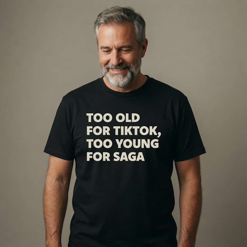 Bearded man smiling and looking down in a black Too Old For TikTok, Too Young For Saga t-shirt, fun and cheeky old-age banter every dad will relate to
