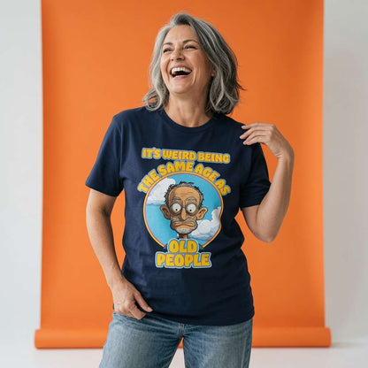 Woman laughing with one hand on her shoulder while wearing a navy It’s Weird Being The Same Age As Old People t-shirt, humorous ladies dad joke graphic design that every no-nonsense lady will claim