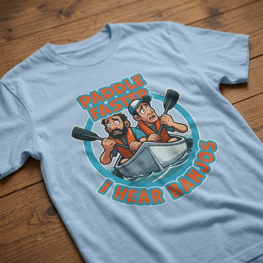 Light blue Paddle Faster I Hear Banjos t-shirt laid flat on a wooden surface showing the full cartoon canoe scene, funny movie-inspired graphic full of classic banter