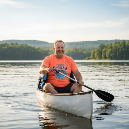 Man paddling a canoe on a calm lake with trees and mountains in the background