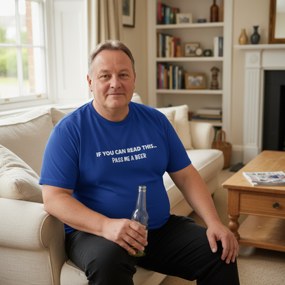 Man in a blue t-shirt holding a beer bottle in a living room.