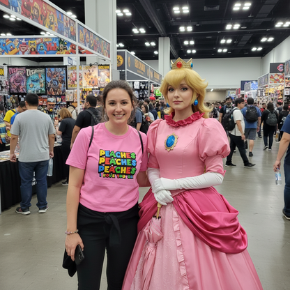 Woman in pink 'PEACHES' t-shirt posing with a character in a pink dress at a convention.