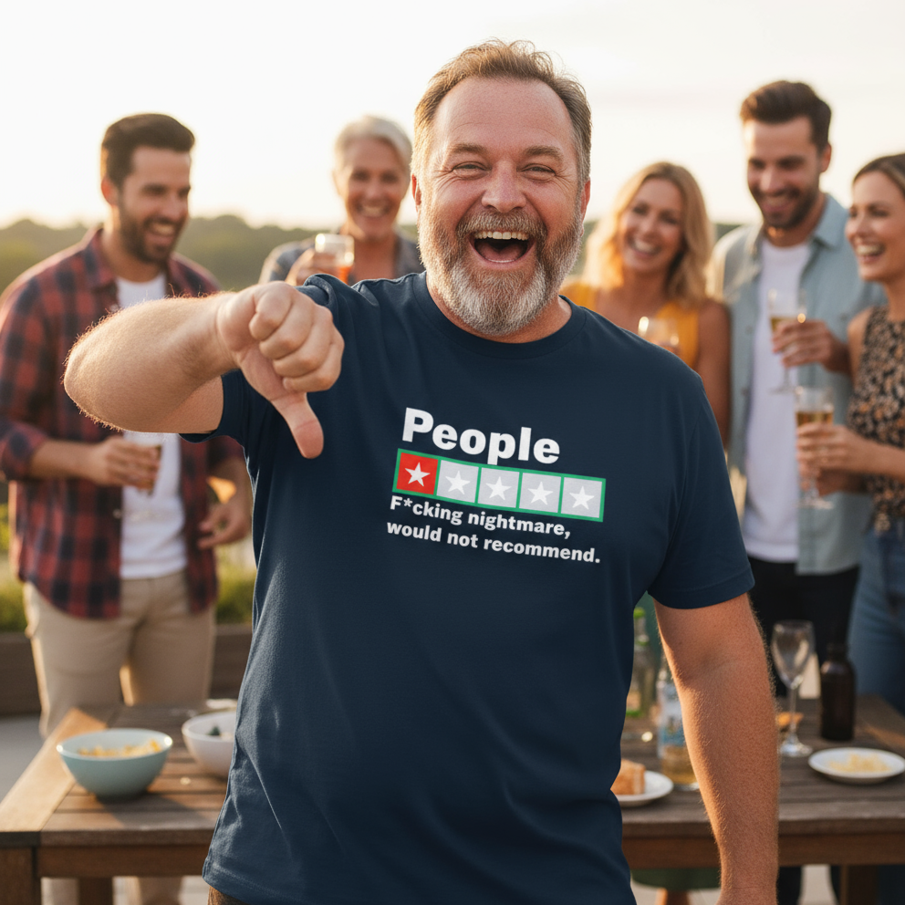 Man wearing a t-shirt with a humorous graphic and text, giving a thumbs down gesture, with friends in the background at a outdoor gathering.