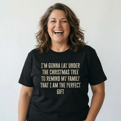Woman laughing openly while wearing a black I’m Gonna Lay Under The Christmas Tree t-shirt, funny ladies xmas day slogan full of pure confidence