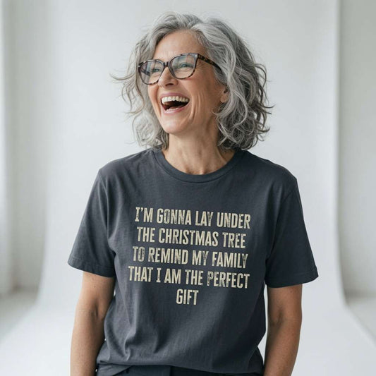 Woman with grey hair and glasses laughing in an ink grey I’m Gonna Lay Under The Christmas Tree t-shirt, fun and witty ladies xmas day banter that every family will recognise