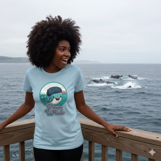woman stood in front of the ocean wearing a light blue t-shirt with the graphic of a whale