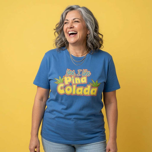 Woman laughing with layered necklaces while wearing a blue Yes, I Like Pina Colada t-shirt, witty ladies funny cocktail pun design full of pure attitude