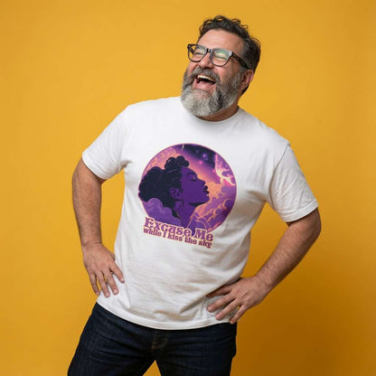 Bearded man with glasses laughing with hands on his hips while wearing a white Excuse Me While I Kiss the Sky t-shirt featuring a purple silhouette against a cosmic background, mens 70s music-inspired purple graphic