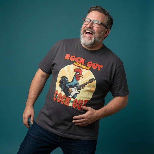 Bearded man with glasses laughing with one hand on his stomach while wearing a black Rock Out with Your Cock Out t-shirt featuring a rooster shredding on guitar, funny mens cockerel graphic pun