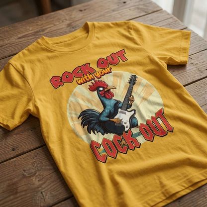 Mustard yellow Rock Out with Your Cock Out t-shirt laid flat on a wooden surface showing the full rooster guitar graphic, fun mens offensive animal design