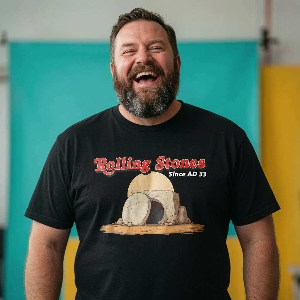 Man laughing while wearing a black Rolling Stones Since AD 33 t-shirt, witty mens offensive jesus easter design that every cheeky lad will claim