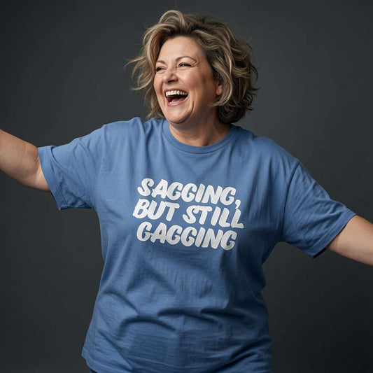 Woman laughing with arms outstretched while wearing a blue Sagging, But Still Gagging t-shirt, cheeky ladies rude witty gift text design