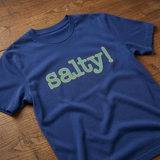 Blue Salty! t-shirt laid flat on a wooden surface with teal outlined text, humorous ladies cheeky slogan design