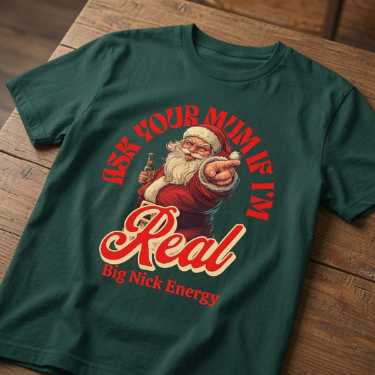 Green Ask Your Mum If I’m Real – Big Nick Energy t-shirt laid flat on a wooden surface showing the full Santa graphic, funny mens Christmas Santa banter design that every big Nick will claim