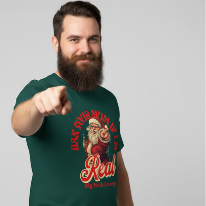 Man wearing a green funny santa t-shirt with a graphic design and the slogan "Ask your mum if i'm real, Big nick energy" pointing forward on a gray background