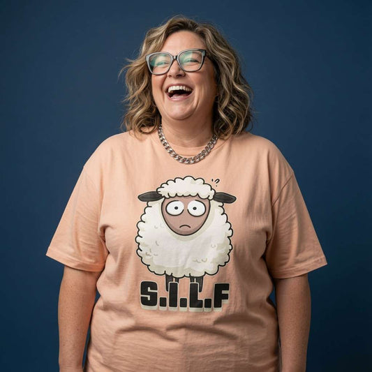 Woman with glasses laughing while wearing a peach S.I.L.F t-shirt with the full confused sheep graphic, witty ladies sheep pun full of pure attitude
