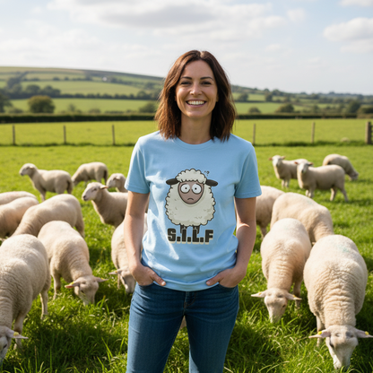 Woman wearing a light blue t-shirt with a sheep graphic in a field of sheep.