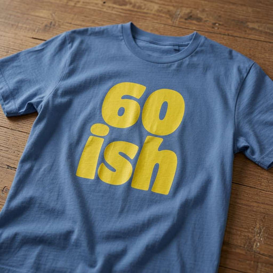 Blue 60 ish t-shirt laid flat on a wooden surface with large yellow text, funny mens 60th birthday gift slogan that every sixty-something lad will claim