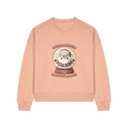 peach christmas sweater with the graphic of santa inside a snowglobe and the slogan 'surrounded by snowflakes'