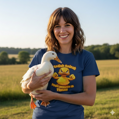 Woman holding a duck in a field wearing a blue t-shirt with a graphic design.