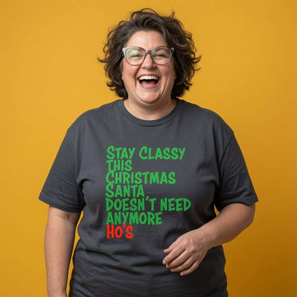 Woman laughing with one hand on her hip while wearing an ink grey Stay Classy This Christmas Santa Doesn’t Need Anymore Ho’s t-shirt, funny ladies rude Xmas slogan shirt that every no-nonsense lady will claim