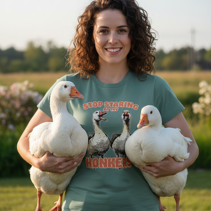 Woman holding two white geese wearing a green t-shirt with a humorous design.