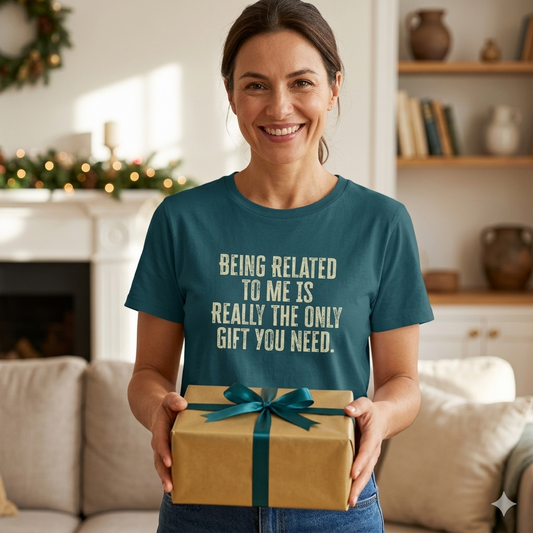 Woman wearing a teal t-shirt with a humorous message, holding a gift in a cozy living room.