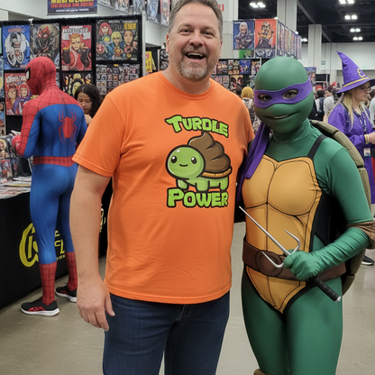 Man wearing an orange 'Turtle Power' shirt standing next to a person in a green turtle costume at a convention.