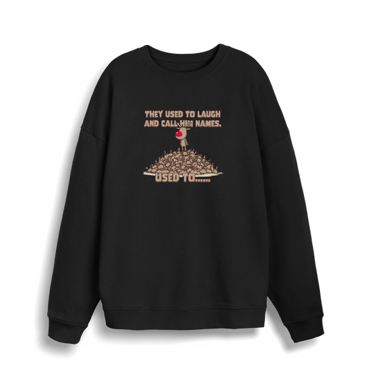black christmas sweater with the graphic of rudolph stood on top of a pile of reindeer and the slogan 'they used to laugh and call him names used to... '