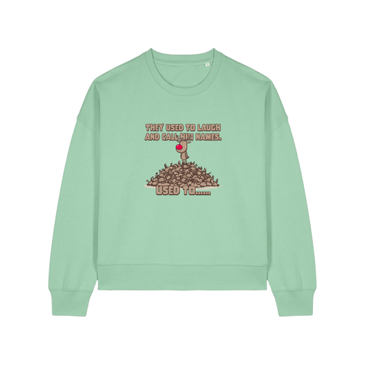 green christmas sweater with the graphic of rudoph stood ontop of a pile of reindeer and the slogan 'they used to laugh and call him names used to ..'