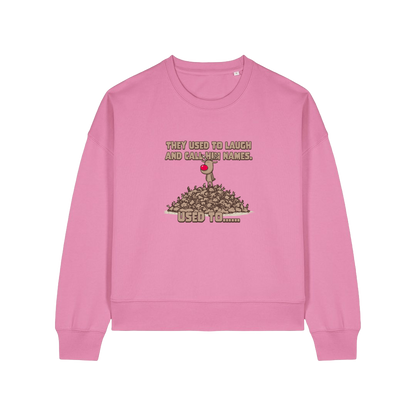 pink christmas sweater with the graphic of rudoph stood ontop of a pile of reindeer and the slogan 'they used to laugh and call him names used to ..'