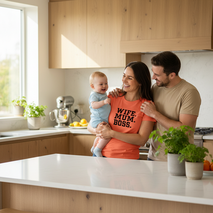 Family of three in a modern kitchen with a woman holding a baby and a man standing next to them.